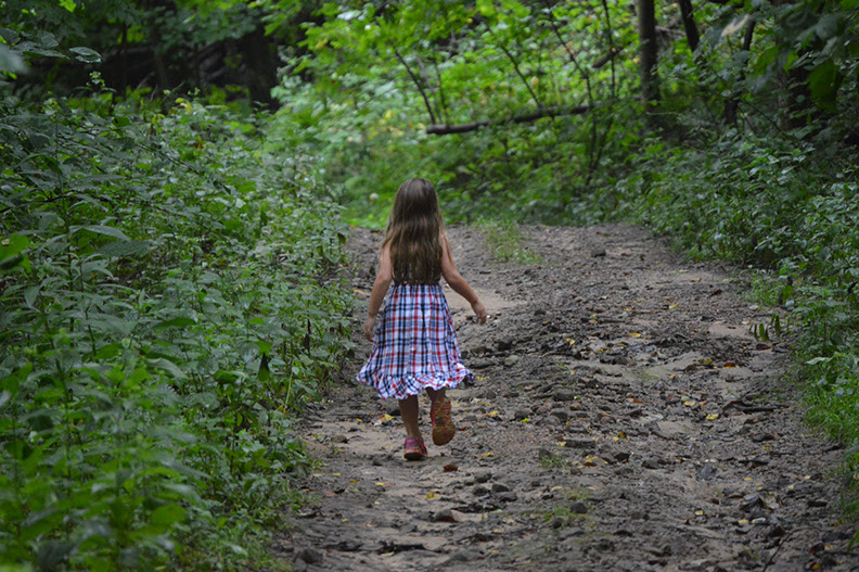 A girl can be seen hiking through the woods at the Woodbury Cabin Rental