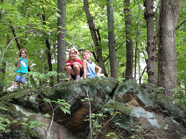 A photo of kids sitting on top of a rock formation.
